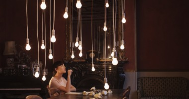 Woman sitting at table with hanging lightbulbs