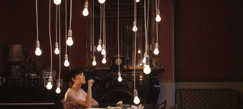 Woman sitting at table with hanging lightbulbs