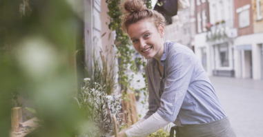 Portrait smiling young female florist arranging display at storefront
