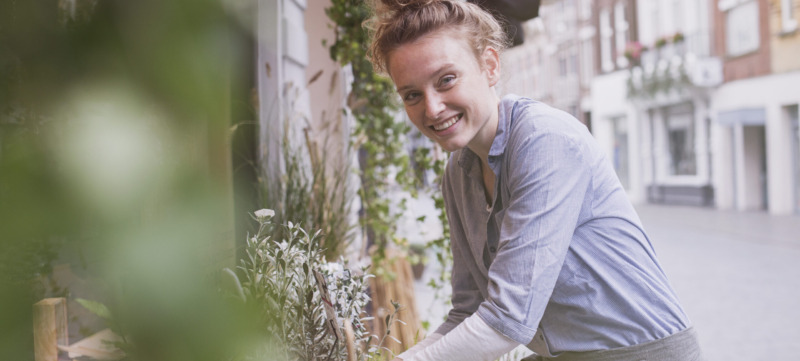 Portrait smiling young female florist arranging display at storefront