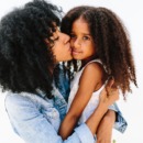 A Mother Giving Her Child A Kiss On The Cheek