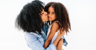 A Mother Giving Her Child A Kiss On The Cheek