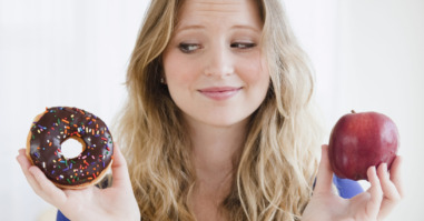 USA, New Jersey, Jersey City, Young woman choosing between donut and apple