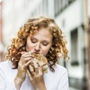 Portrait of young woman eating bagel outdoors
