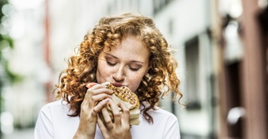 Portrait of young woman eating bagel outdoors