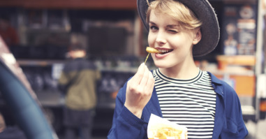 Portrait of young woman with fries winking