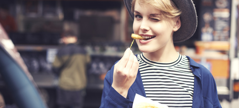 Portrait of young woman with fries winking