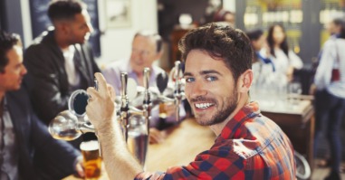 Portrait smiling, confident male bartender serving beer at bar