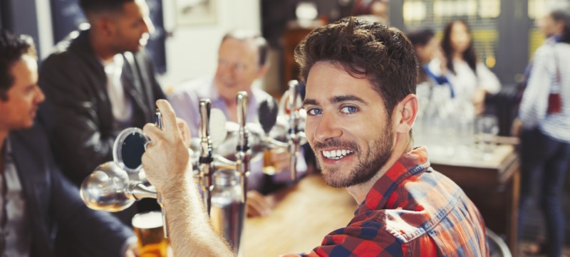 Portrait smiling, confident male bartender serving beer at bar