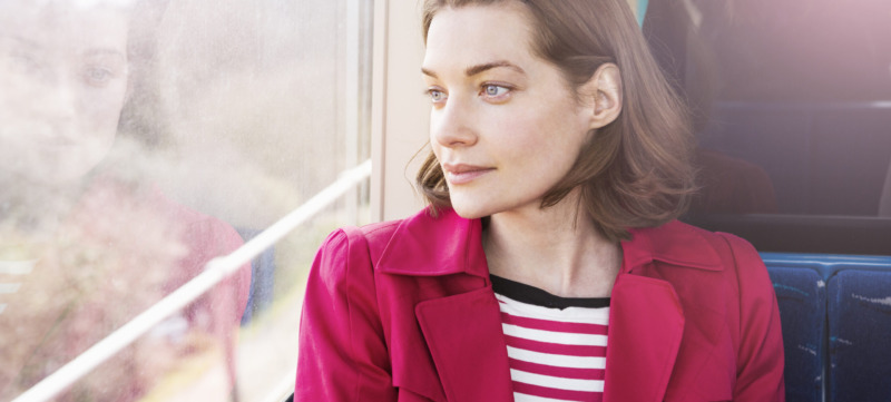 Woman sitting in train looking out of window.