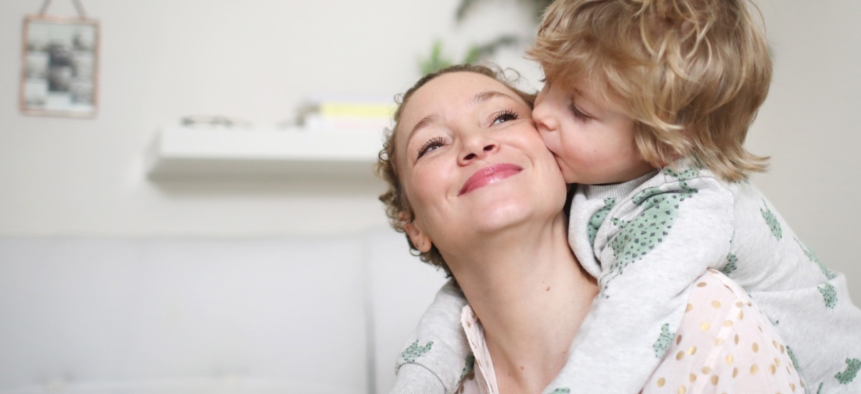 A little boy taking his mum in his arms in the bedroom