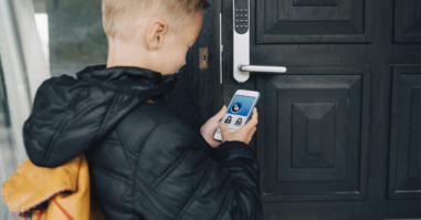 Rear view of boy using app on smart phone to unlock house door