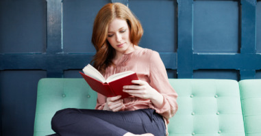Woman reading a book on sofa.