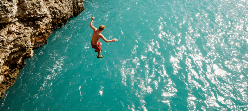 iemand springt op vakantie van een klif in het water