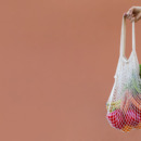 Woman Holding Reusable Cotton Mesh Bag With Fruit And Vegetables
