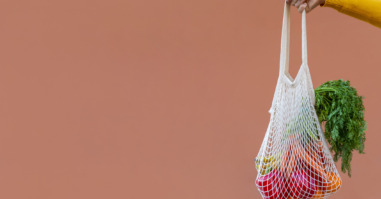 Woman Holding Reusable Cotton Mesh Bag With Fruit And Vegetables