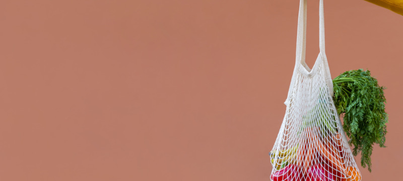 Woman Holding Reusable Cotton Mesh Bag With Fruit And Vegetables