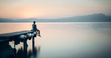 Italy, Lazise, man sitting on jetty looking at Lake Garda