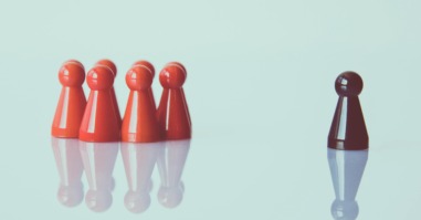 een groep met rode poppetjes staan links en één zwart poppetje staat rechts
