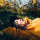 Beautiful woman lies on the grass with closed eyes.