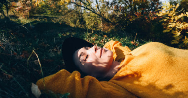 Beautiful woman lies on the grass with closed eyes.