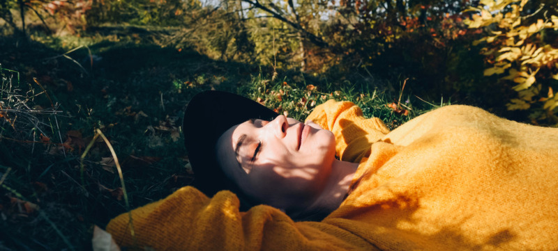 Beautiful woman lies on the grass with closed eyes.