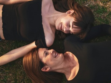 een moeder en haar dochter liggen in het gras
