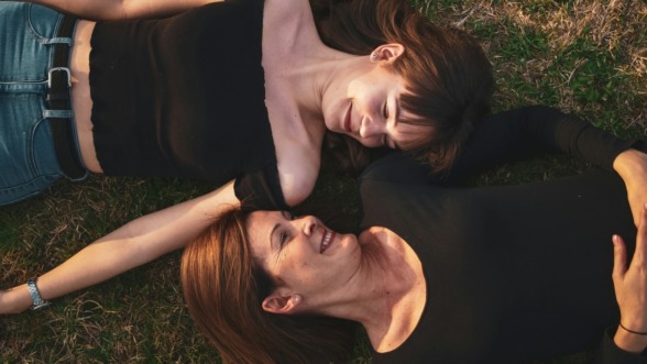 een moeder en haar dochter liggen in het gras