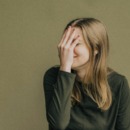 vrouw slaat zichzelf voor haar gezicht en bloost omdat ze iets beschamends deed