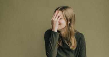 vrouw slaat zichzelf voor haar gezicht en bloost omdat ze iets beschamends deed