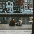 twee mensen praten met elkaar aan de gracht in amsterdam en besteden hun vrije tijd samen