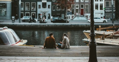 twee mensen praten met elkaar aan de gracht in amsterdam en besteden hun vrije tijd samen