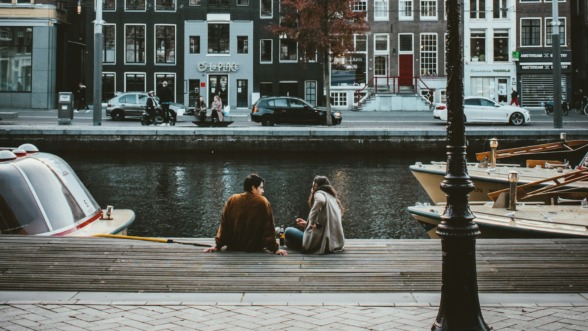 twee mensen praten met elkaar aan de gracht in amsterdam en besteden hun vrije tijd samen