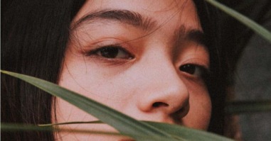 vrouw verborgen achter een plantenblad