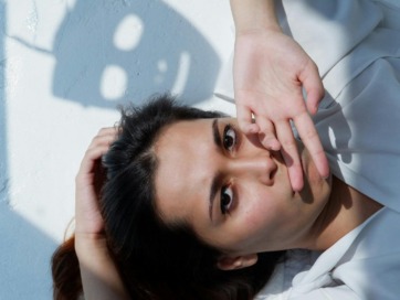 vrouw met handen voor de mand en masker als schaduw op de muur