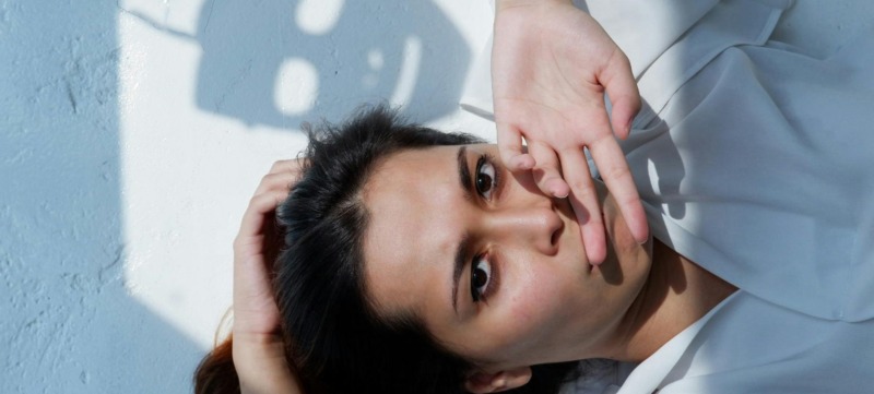 vrouw met handen voor de mand en masker als schaduw op de muur