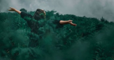 vrouw met armen gespreid in natuur als beeld bij tekst over veerkracht door natuur