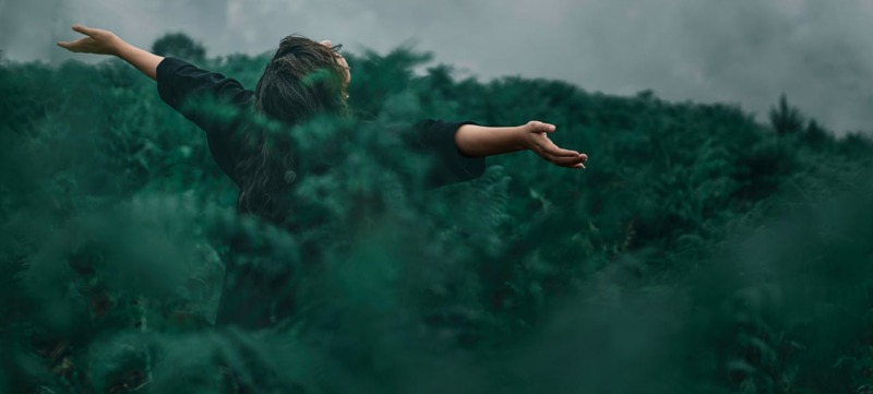 vrouw met armen gespreid in natuur als beeld bij tekst over veerkracht door natuur
