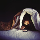 kind zit op haar smartphone in bed