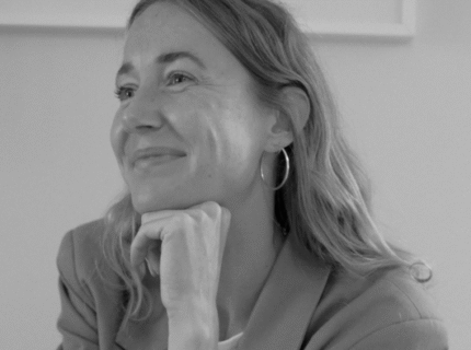 Lisanne van Marrewijk kijkt schuin langs de camera en lacht. De foto is in zwart wit beeld.