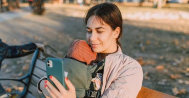 Moeder zit op haar telefoon waar haar baby bij is
