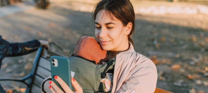 Moeder zit op haar telefoon waar haar baby bij is