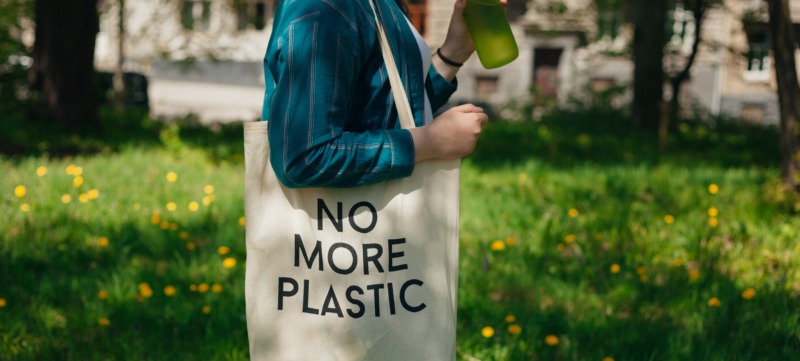 vrouw loopt met een canvas tasje met de tekst 'no more plastic'