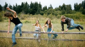 drie kinderen springen over een hek