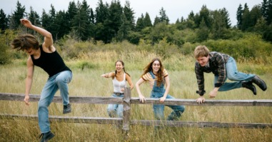drie kinderen springen over een hek