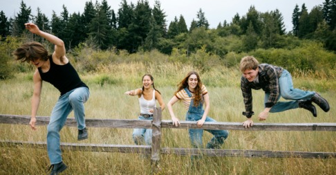 drie kinderen springen over een hek