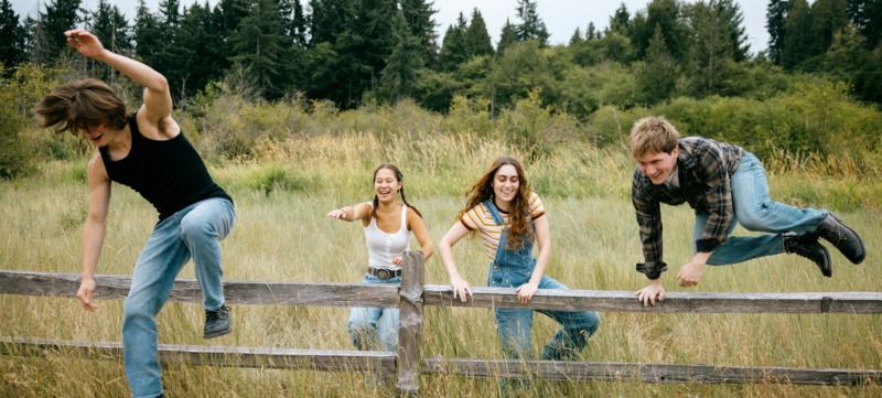 drie kinderen springen over een hek