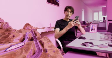 Jacob zittend aan zijn bureau met zijn telefoon in zijn hand, met een foto van Ava ingelijst op zijn bureau.