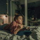 Vrouw die sushi eet en een serie aan het bingewatchen is in bed.