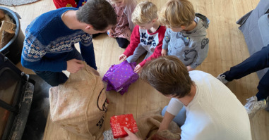 Kinderen pakken cadeautjes uit op pakjesavond.
